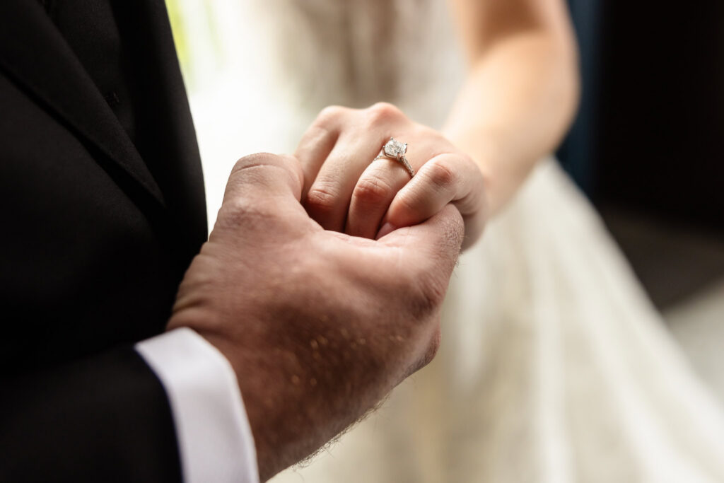 Close-up of the bride's engagement ring as the couple holds hands before their Harbor Club at Prime wedding.