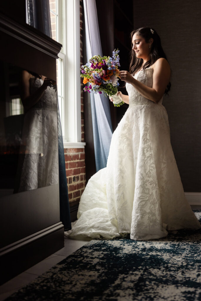 Bride holding her colorful bouquet by a window before her Harbor Club at Prime wedding in Huntington, NY.