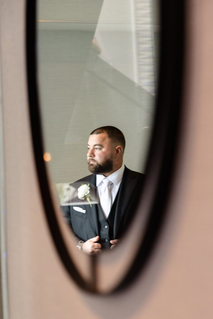 Groom portrait reflected in a mirror while preparing for the Harbor Club at Prime wedding.