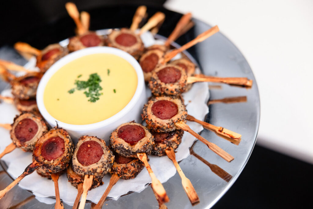 Gourmet pigs in a blanket appetizer served with dipping sauce during wedding cocktail hour.