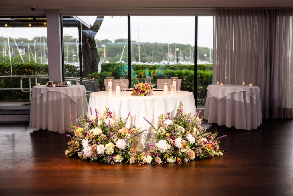 Romantic sweetheart table with lush floral arrangements and waterfront views.