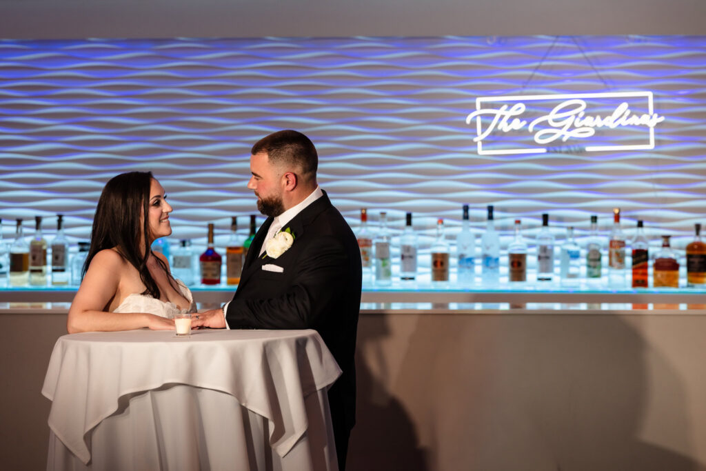 Bride and groom share a quiet moment beneath the illuminated bar.