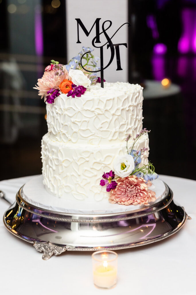 Elegant two-tier wedding cake decorated with fresh flowers.