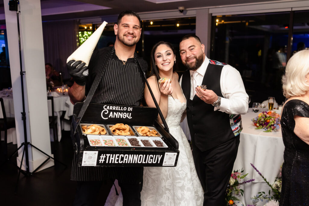 Bride and groom enjoying fresh cannoli from a live dessert station during reception.