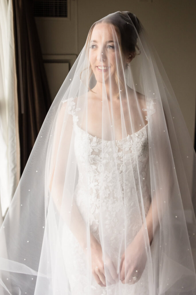 Lauren smiles beneath her pearl-detailed wedding veil while getting ready before the ceremony.