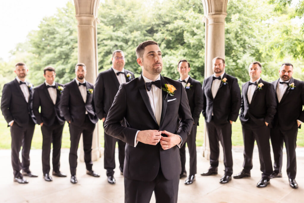 Joe stands with his groomsmen before the ceremony wearing a classic black tuxedo at his Long Island wedding.