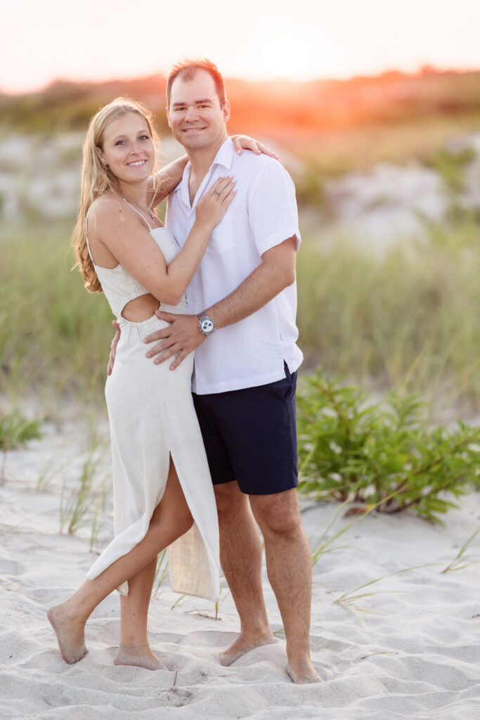 Engaged couple embracing barefoot in the sand during sunset at Robert Moses State Park.