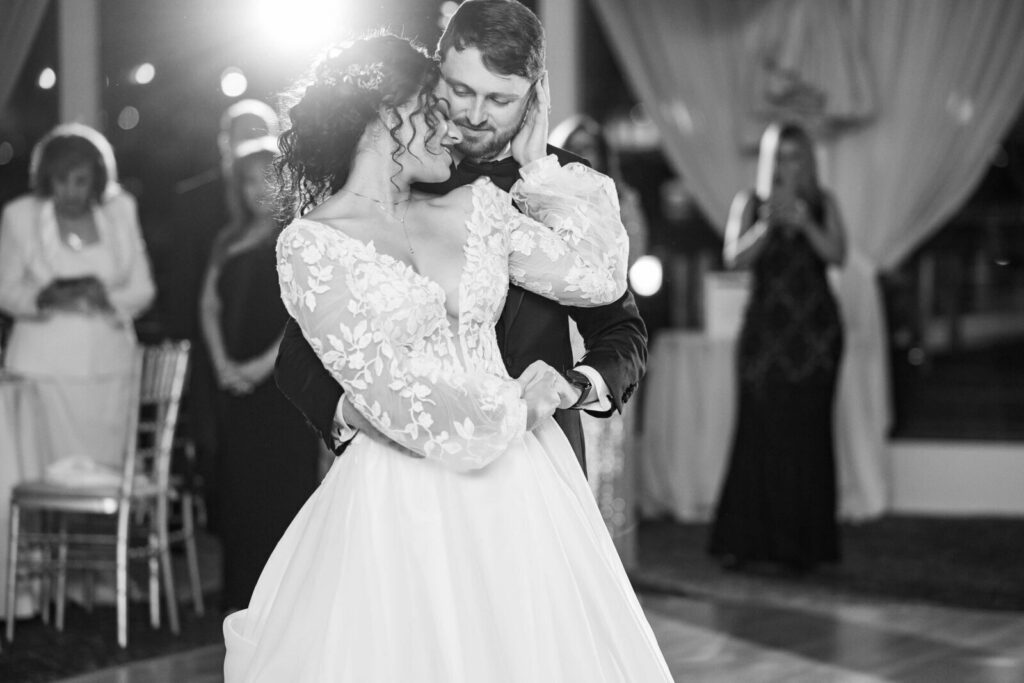 Black-and-white photograph of newlyweds embracing during an intimate first dance at their wedding reception showing how much their Long Island wedding cost.