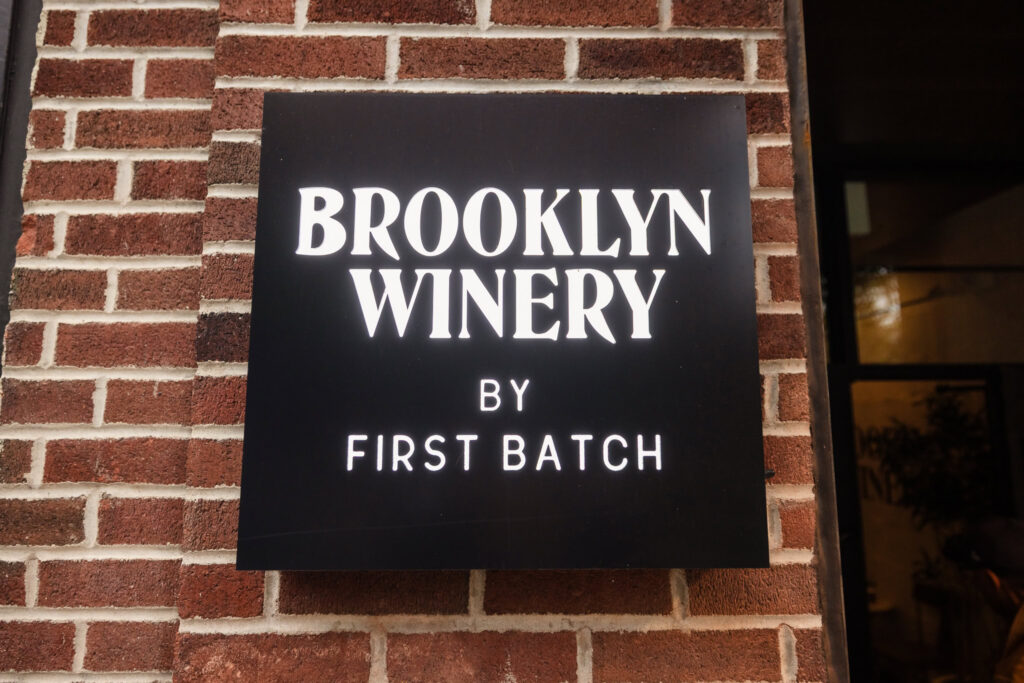 Brooklyn Winery by First Batch sign mounted on the brick exterior of the Williamsburg wedding venue.