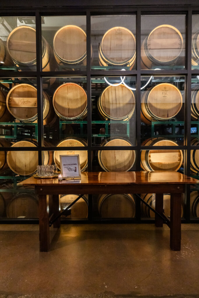 Wine barrels stacked behind glass inside the barrel room.
