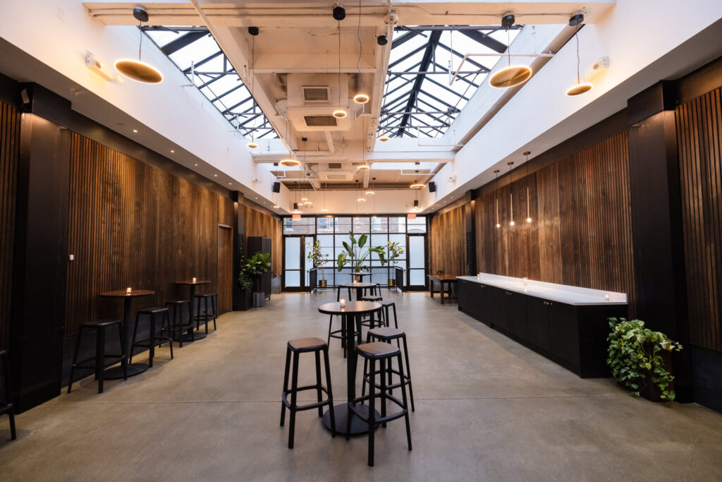 Brooklyn Winery event space with dark wood walls, cocktail tables, and large overhead skylights.