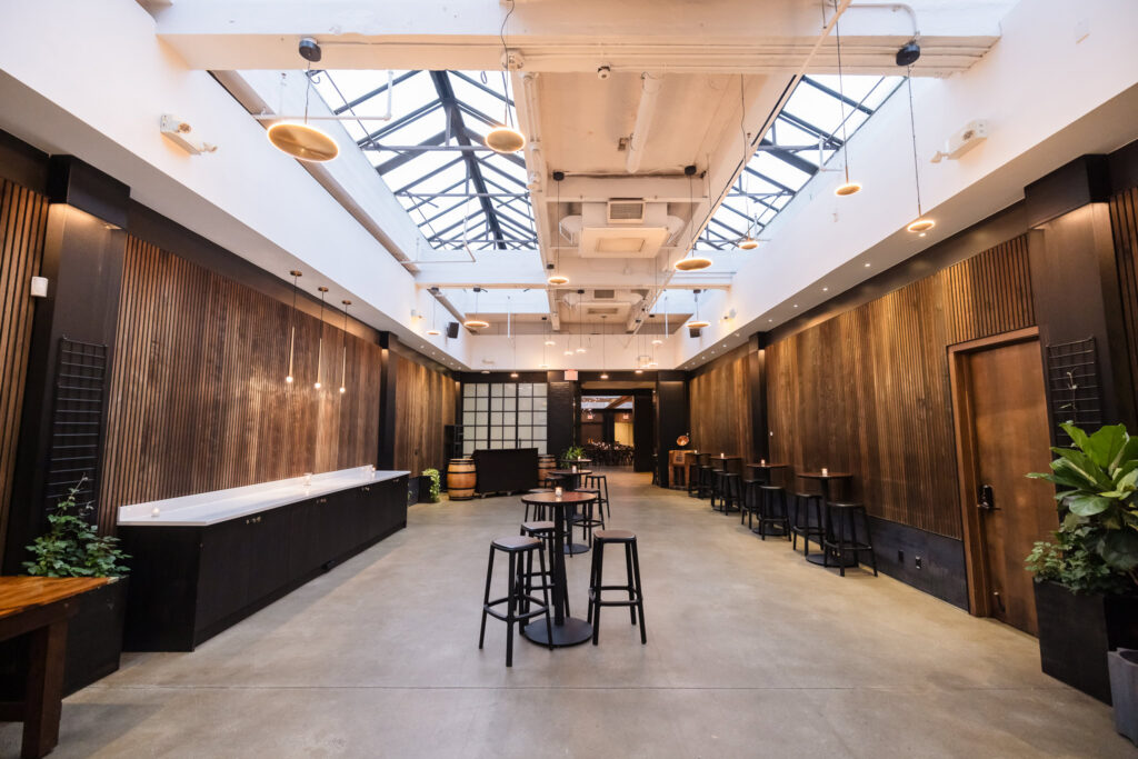Wide view of the reception room with skylights, cocktail tables, wood walls, and polished concrete floors.