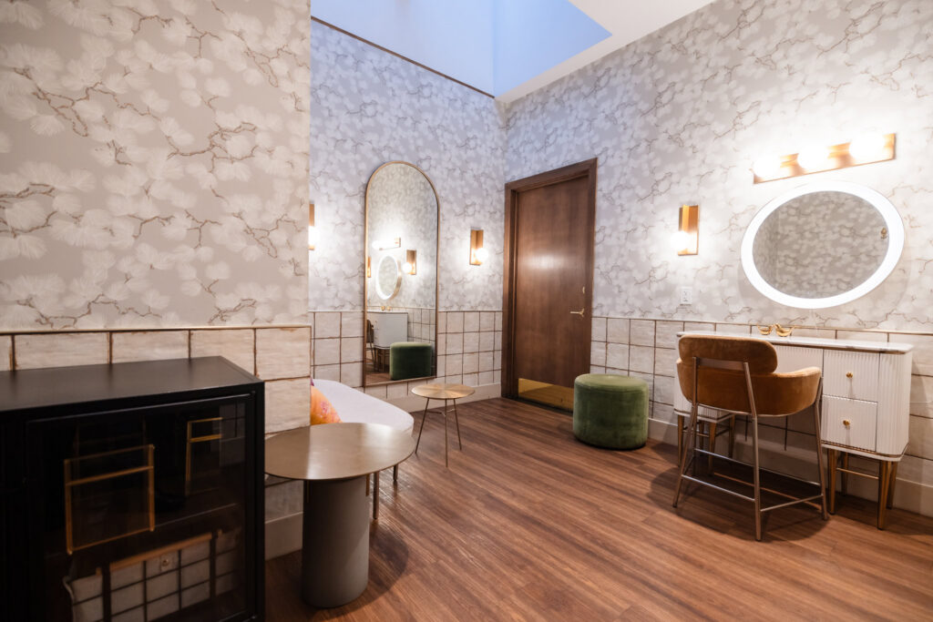 Brooklyn Winery wedding suite with vanity, mirrors, lounge seating, floral wallpaper, and warm wood flooring.