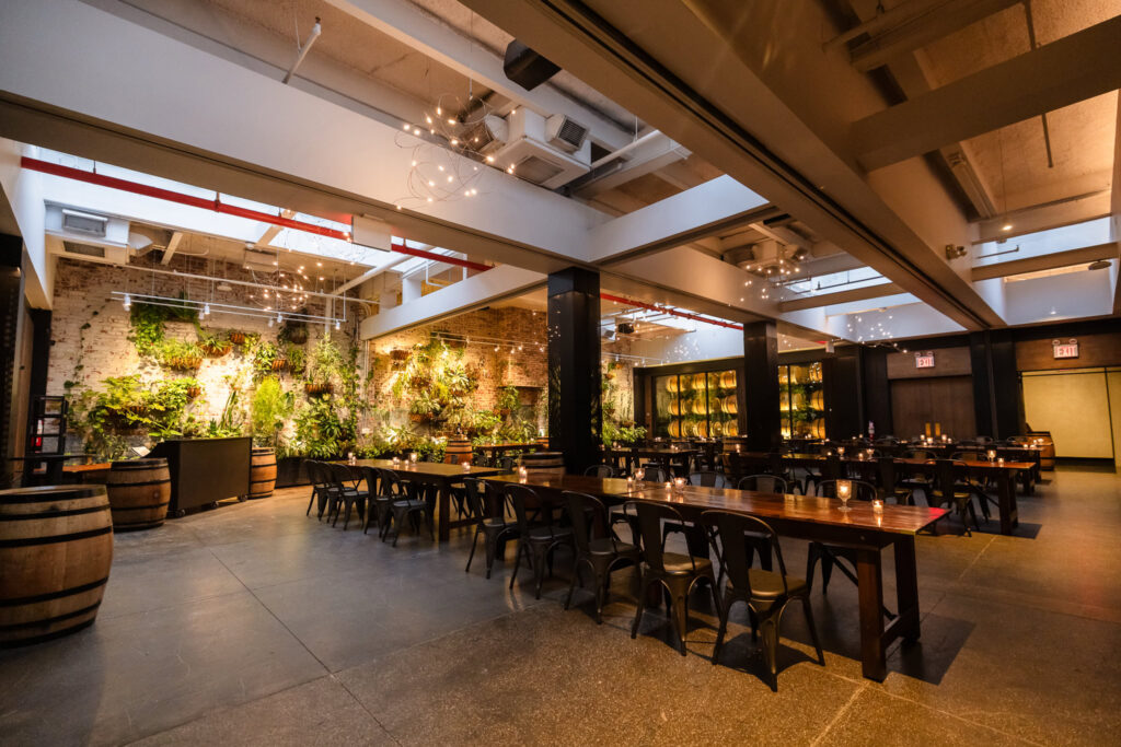 Brooklyn Winery reception space set with long wooden tables, candlelight, wine barrels, and its signature living plant wall.