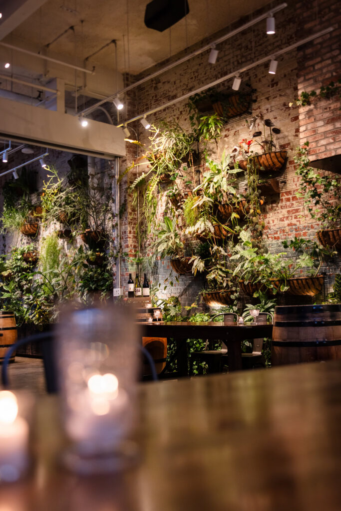 Candlelit tables overlooking the lush living plant wall and exposed brick inside Brooklyn Winery.
