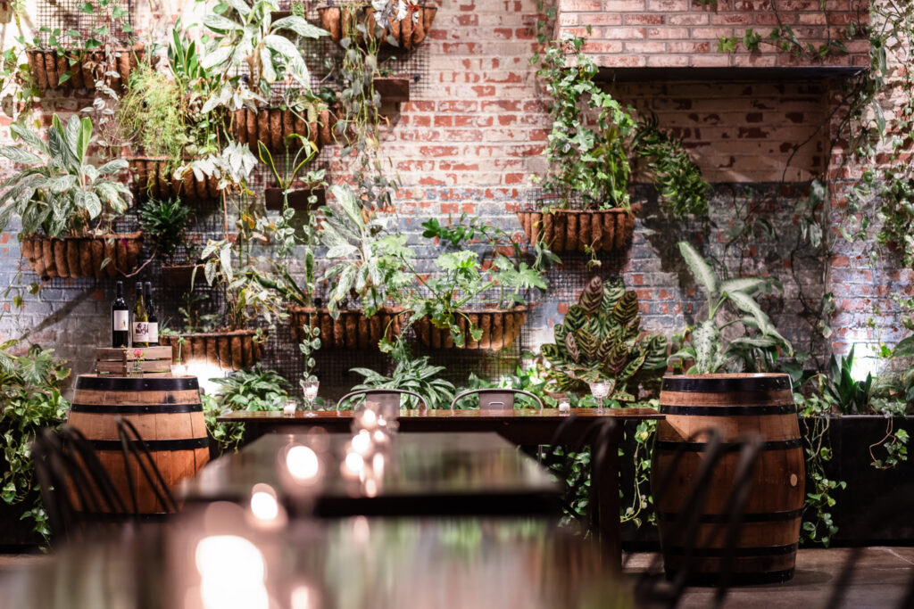 Reception table framed by wine barrels and greenery along Brooklyn Winery's living plant wall.