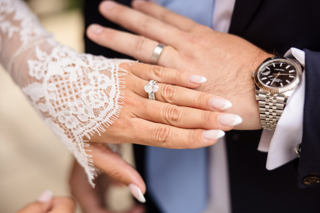 Close-up of the bride and groom’s hands showing their wedding rings alongside the groom’s watch.