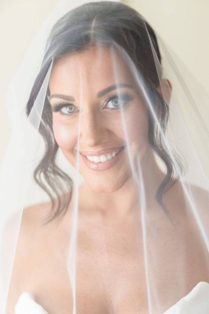 Christine smiles beneath her wedding veil during a softly lit bridal portrait at The Muttontown Club.