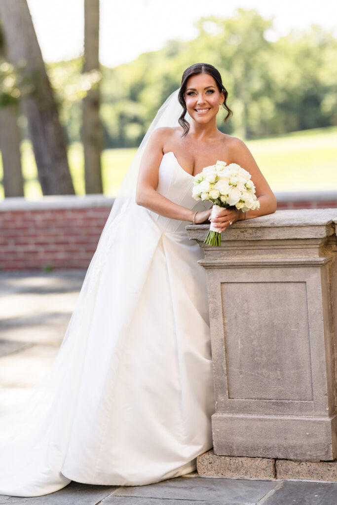 Christine poses with her white rose bouquet in an elegant bridal portrait at The Muttontown Club on Long Island.