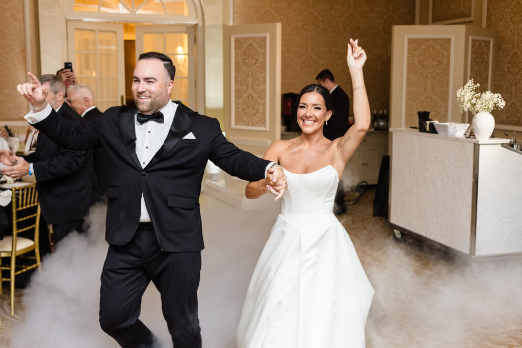 Smiling bride and groom making their grand entrance into their Muttontown Club wedding reception.