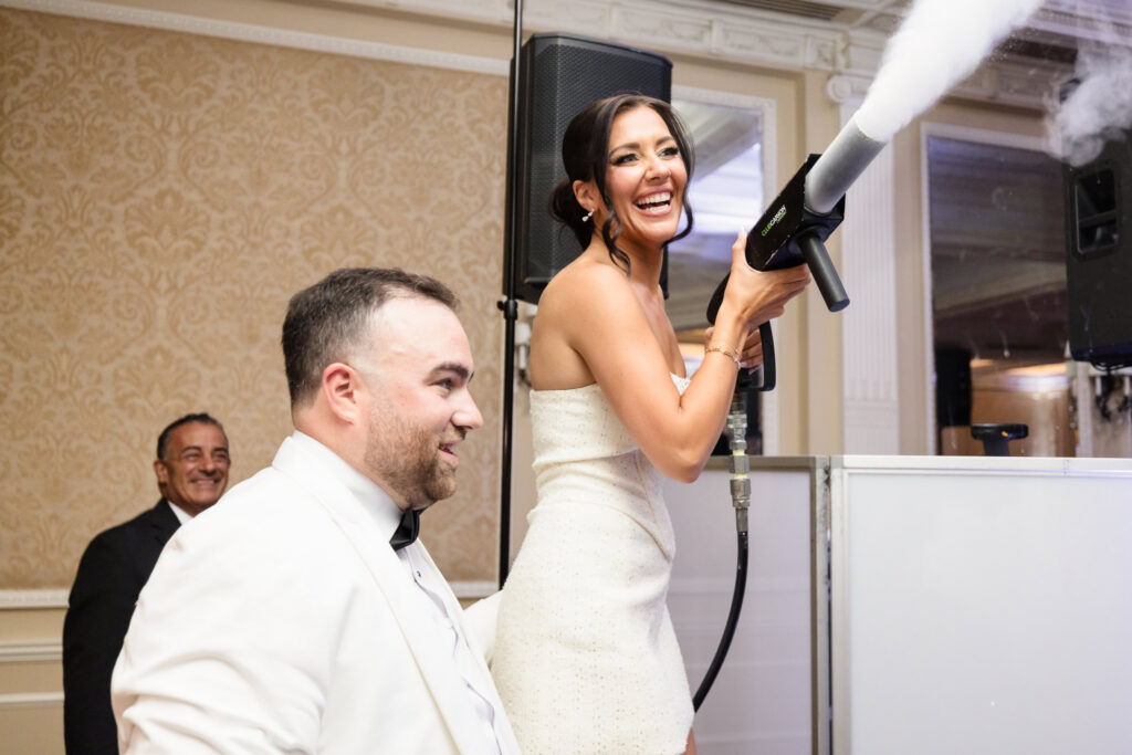 Bride laughing while using a CO2 cannon during the energetic wedding reception.