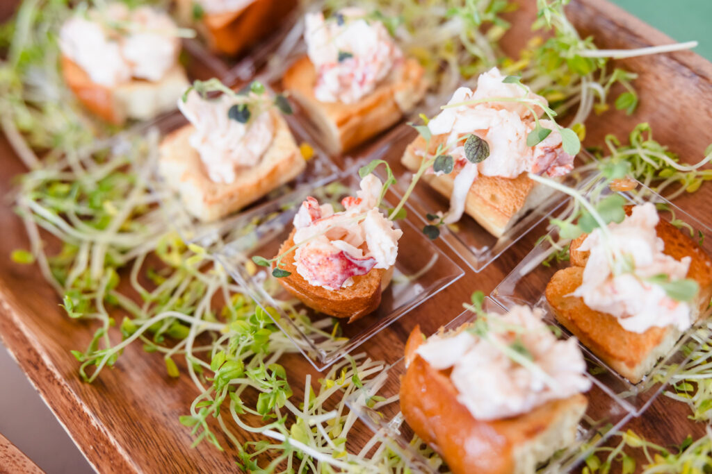 Passed hors d'oeuvres arranged on a wooden serving tray during a waterfront event at EHP Resort.