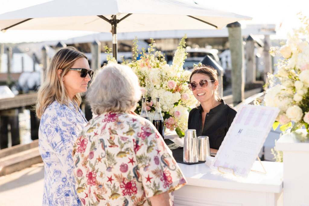 Guests gathering around a flower-filled cocktail bar beside the marina at EHP Resort in East Hampton.