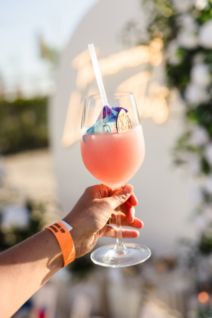 Pink signature cocktail held up in the golden evening light at EHP Resort in East Hampton.