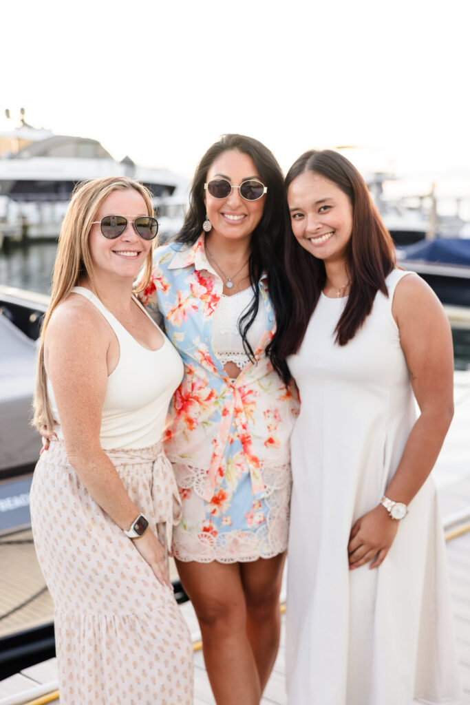 Three guests posing together beside the marina during a summer event at EHP Resort.