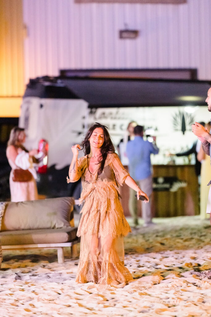 Guest dancing on the sand during a nighttime waterfront celebration.