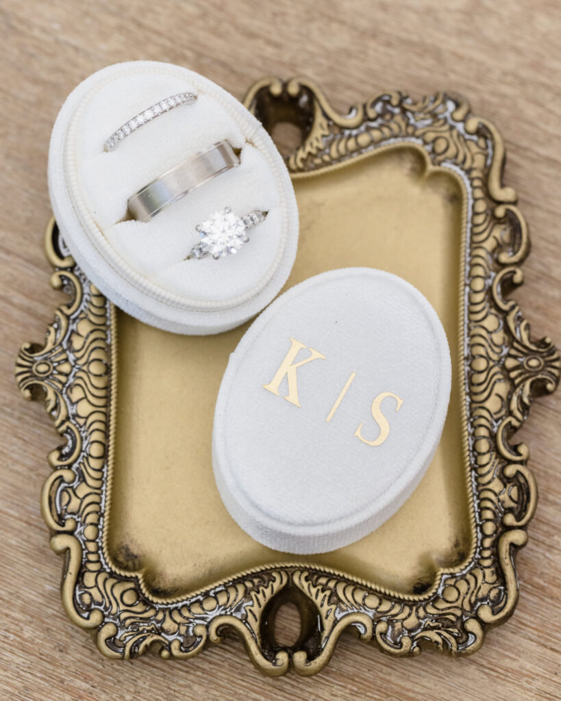 Kaity and Sean’s wedding rings arranged in white velvet ring boxes on an antique gold tray on July 4th wedding.