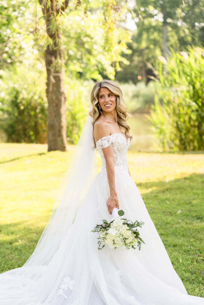 Kaity holding her white bouquet during a sunlit bridal portrait in the Flowerfield gardens.