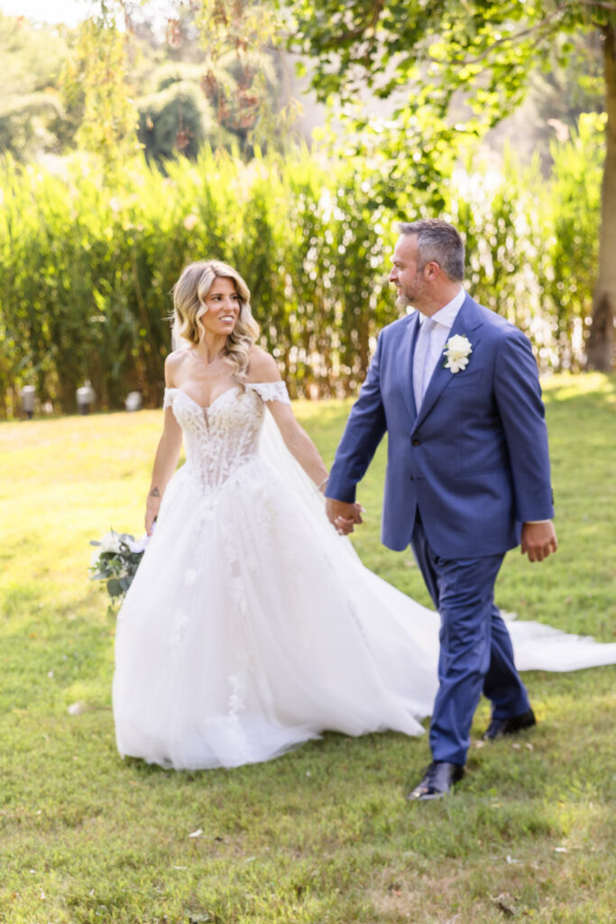 Kaity and Sean walking hand in hand through the gardens during their July 4th wedding at Flowerfield.