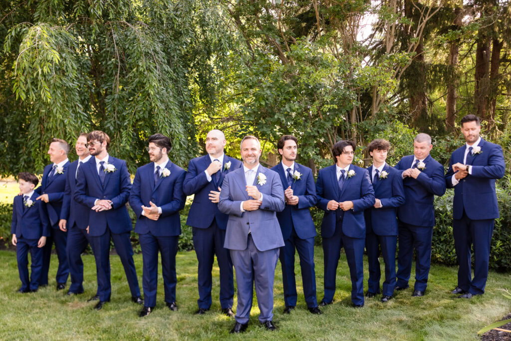 Sean surrounded by his groomsmen in blue suits during wedding party portraits at Flowerfield.