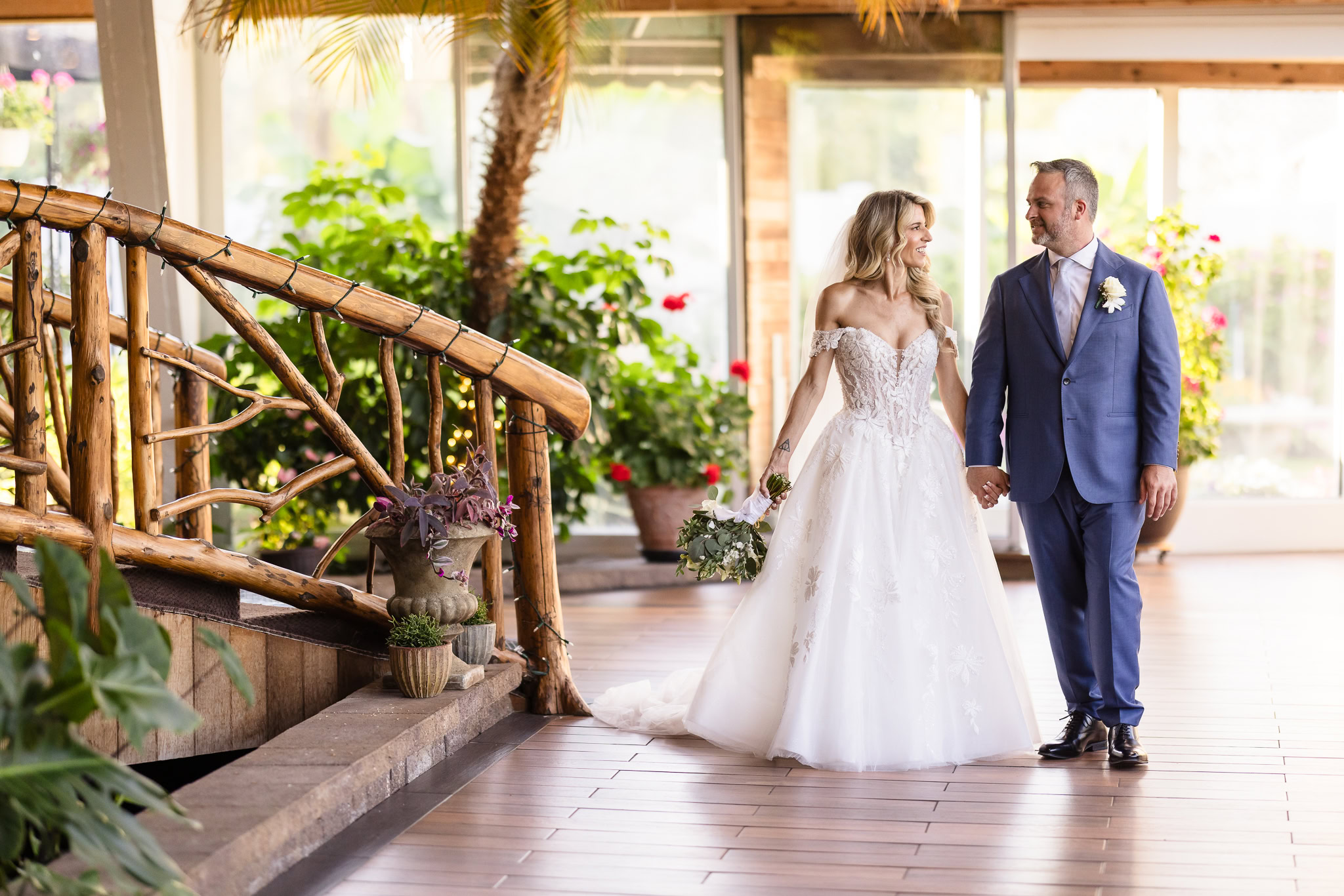 Kaity and Sean walking hand in hand through the garden atrium at their Flowerfield wedding in St. James.