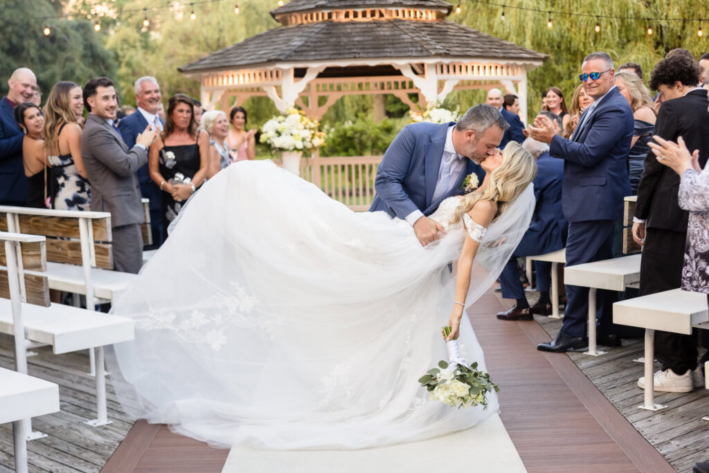 Kaity and Sean celebrating with a kiss as they walk back down the aisle after their Flowerfield wedding ceremony.