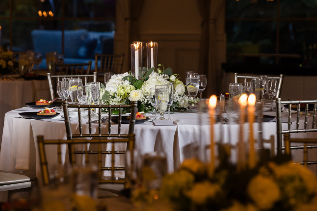 White floral centerpiece, candlelight, and elegant table settings inside the Flowerfield wedding reception on July 4th wedding.