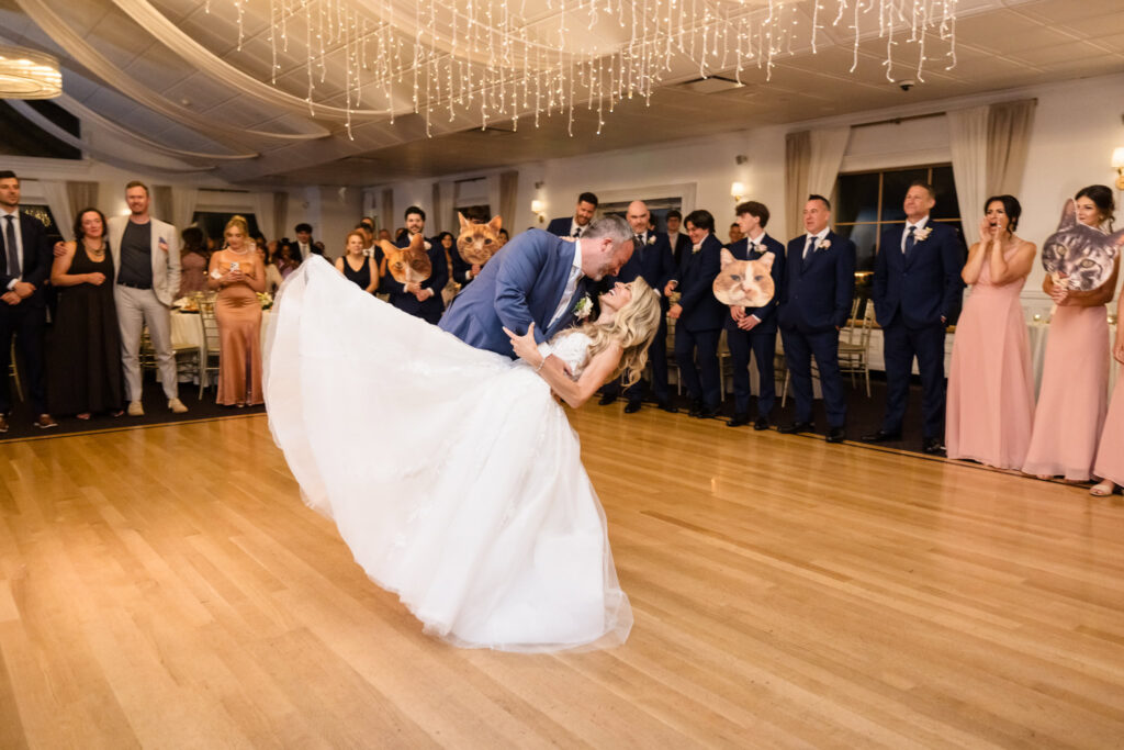 Kaity and Sean sharing a playful dip during their first dance as their wedding party watches at Flowerfield.