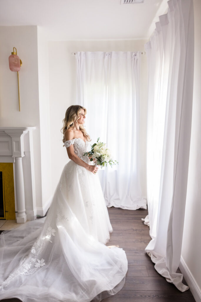 Kaity holding her white bouquet in her wedding gown inside the Rose Cottage at Flowerfield.