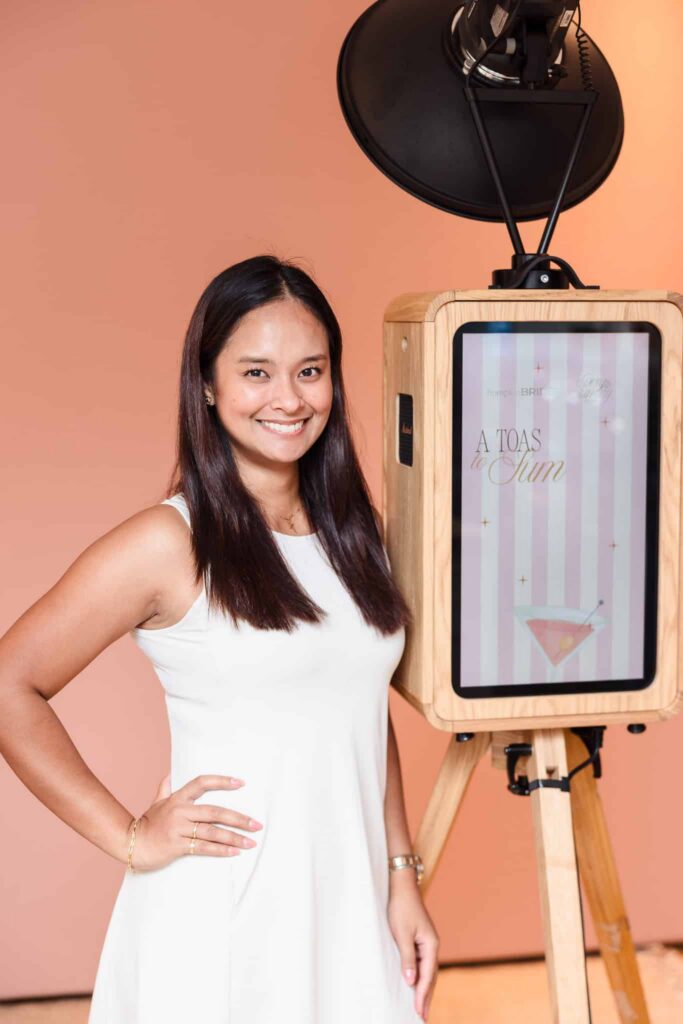 Photo booth attendant beside a branded hamptonBRIDE display at A Toast to Summer in East Hampton.