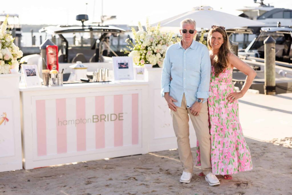 Guests posing beside the hamptonBRIDE cocktail bar with boats and Three Mile Harbor in the background.