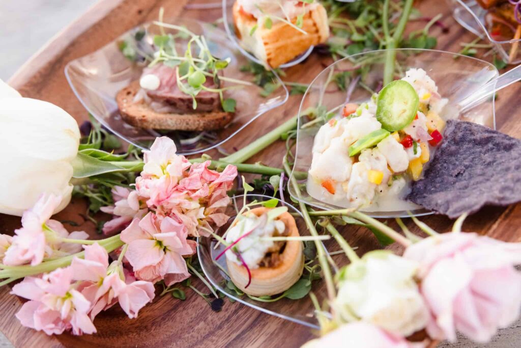 Assorted passed appetizers with fresh flowers presented at the Hamptons wedding industry event.
