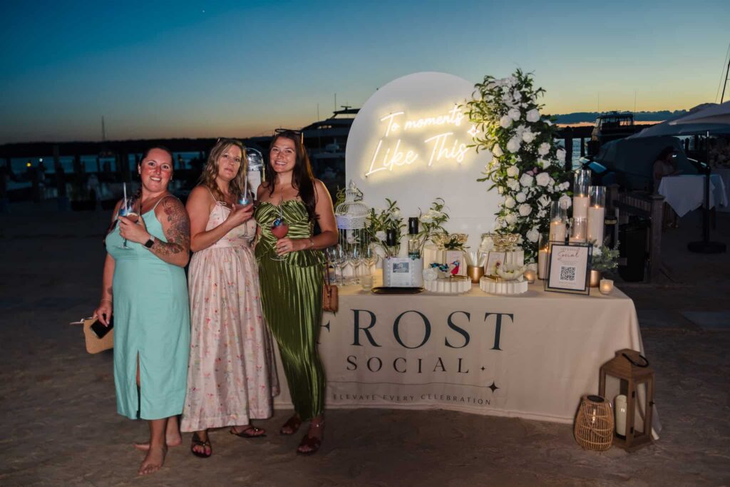 Guests beside the illuminated Frost Social display overlooking the marina after sunset at EHP Resort.