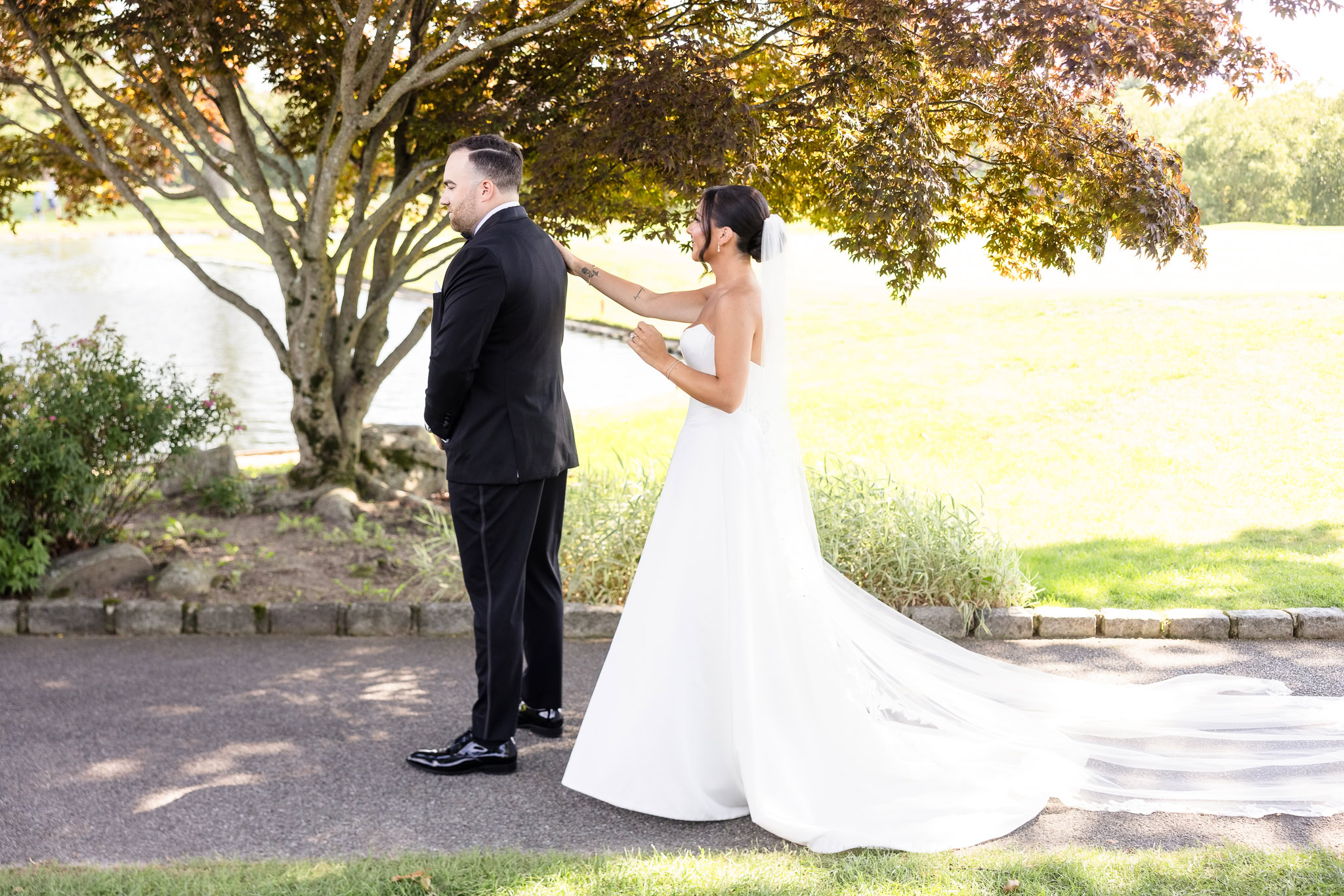 Christine approaches Matt for their first look beneath a tree overlooking the grounds at The Muttontown Club.