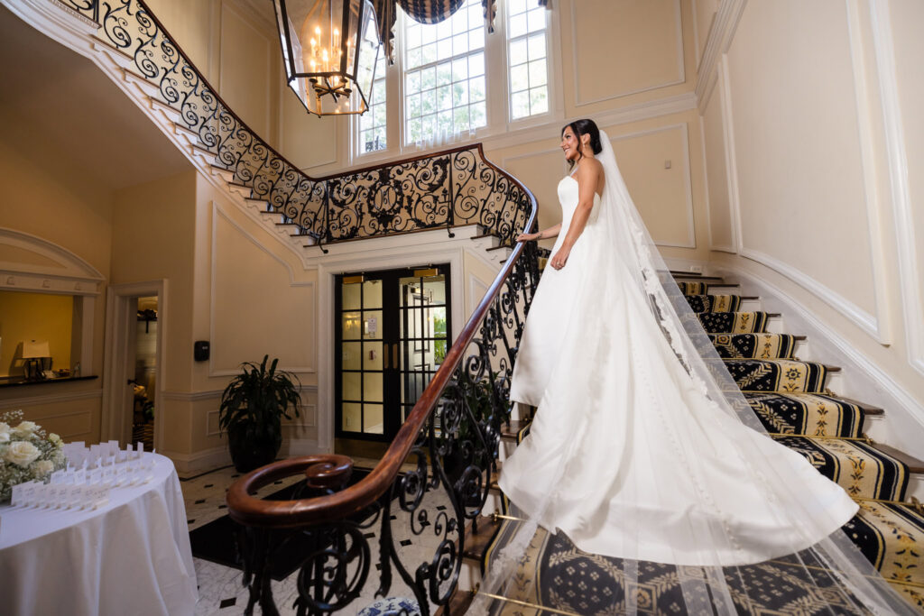 Bride standing on the grand staircase inside The Muttontown Club before her Long Island wedding ceremony.