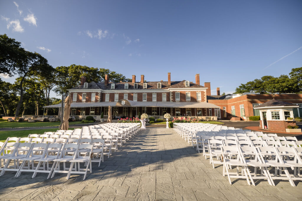 The Muttontown Club mansion with white ceremony chairs arranged on the lawn for an outdoor wedding.