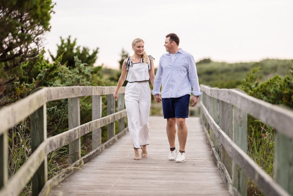 Emily and Corbin walk hand in hand along the Robert Moses boardwalk during their Long Island engagement session.