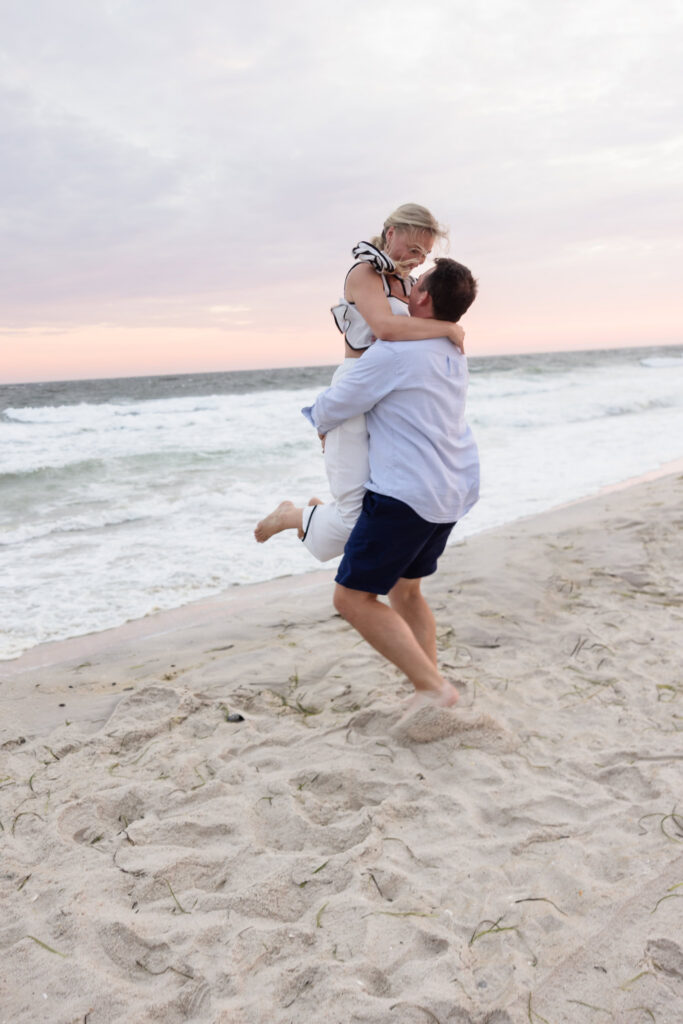 Corbin lifts Emily beside the ocean during their playful beach at Robert Moses.