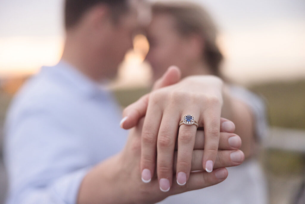Close-up of Emily's blue gemstone engagement ring as she holds Corbin's hand during their Long Island engagement session.