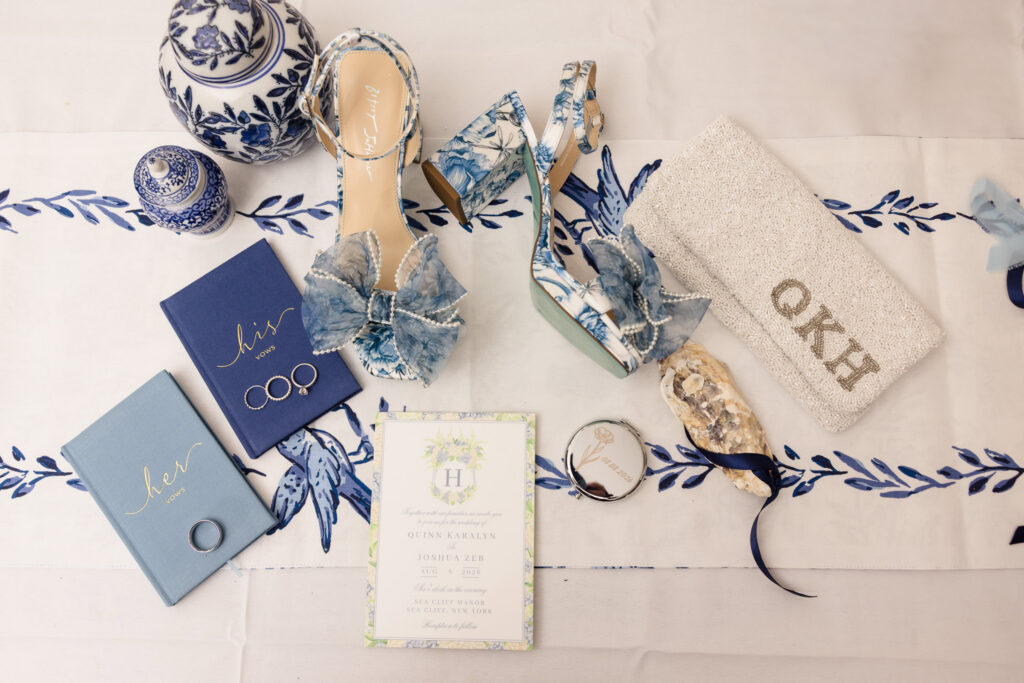 Blue and white wedding details including bridal shoes, vow books, rings, invitation, clutch, and decorative pieces.